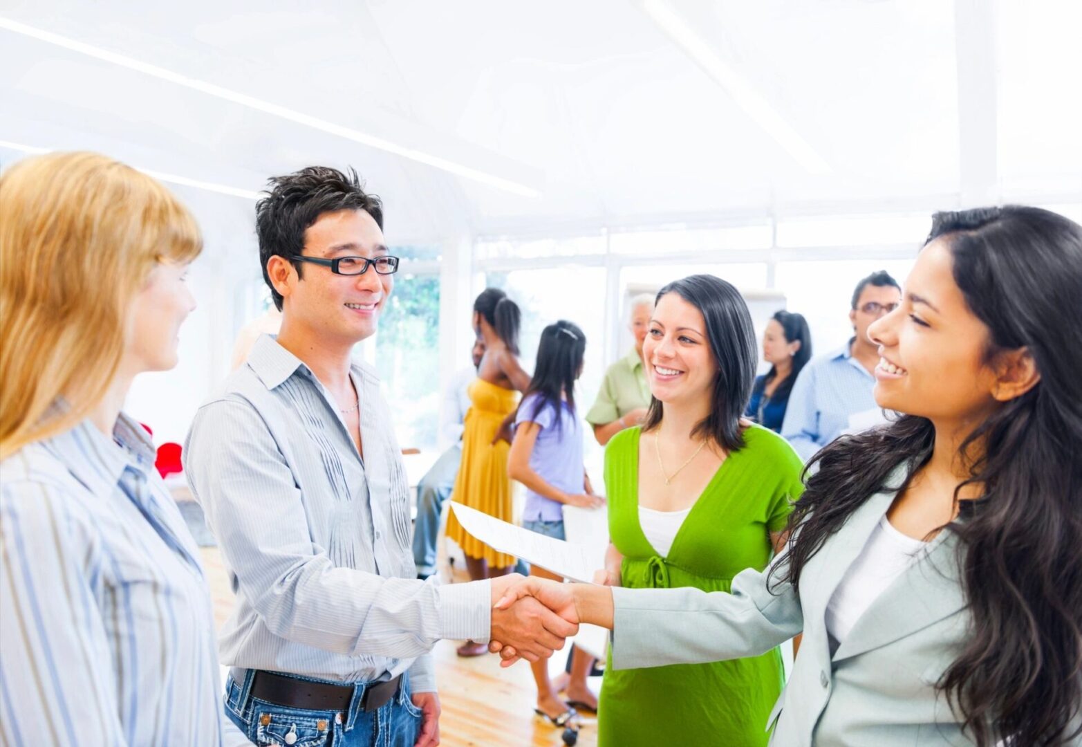 A group of people shaking hands in front of an audience.